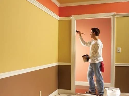 Painter cutting in a terracotta ceiling line above yellow walls, floor sheeted and paint tins ready