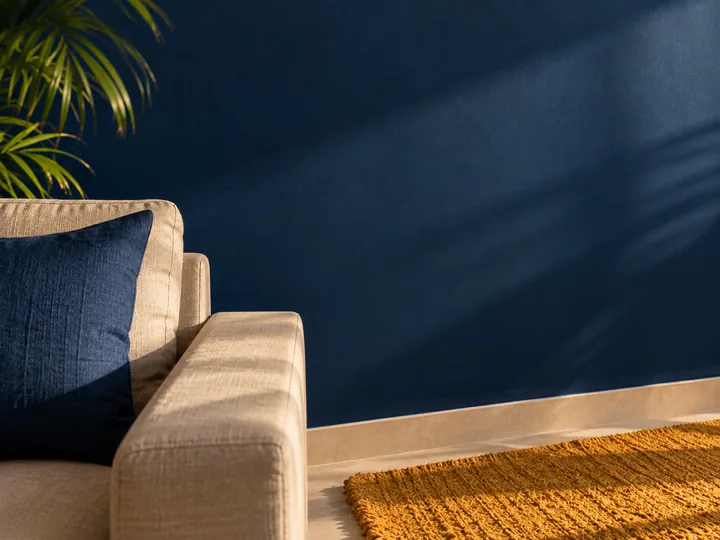 Deep blue living room wall with a warm ochre rug