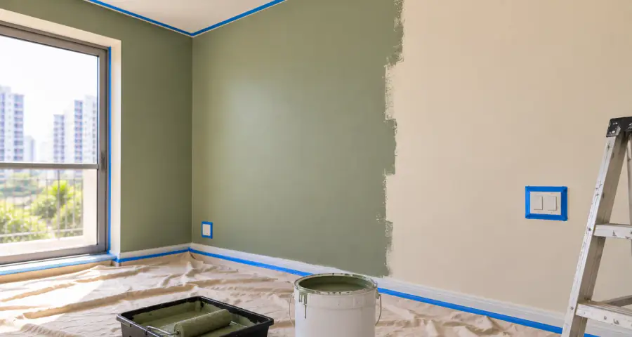 A room mid-job — sheeting down, sockets masked, tins open and the first wall cut in