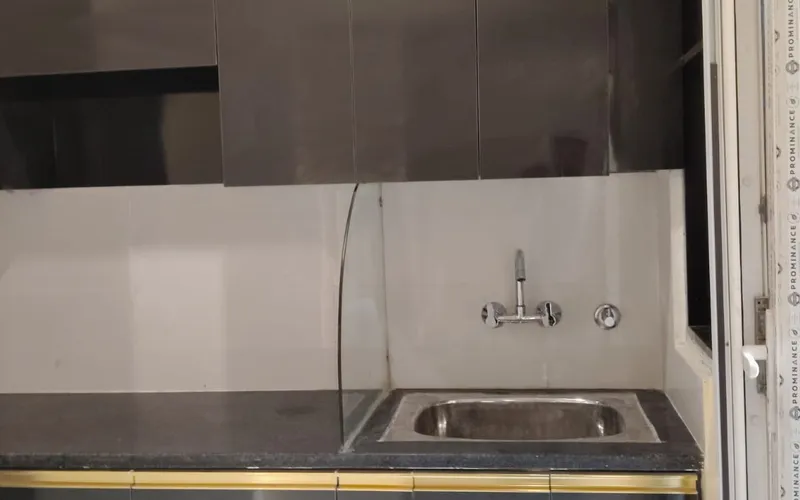 Kitchen counter with a steel sink, dark tiled splashback and finished wall above
