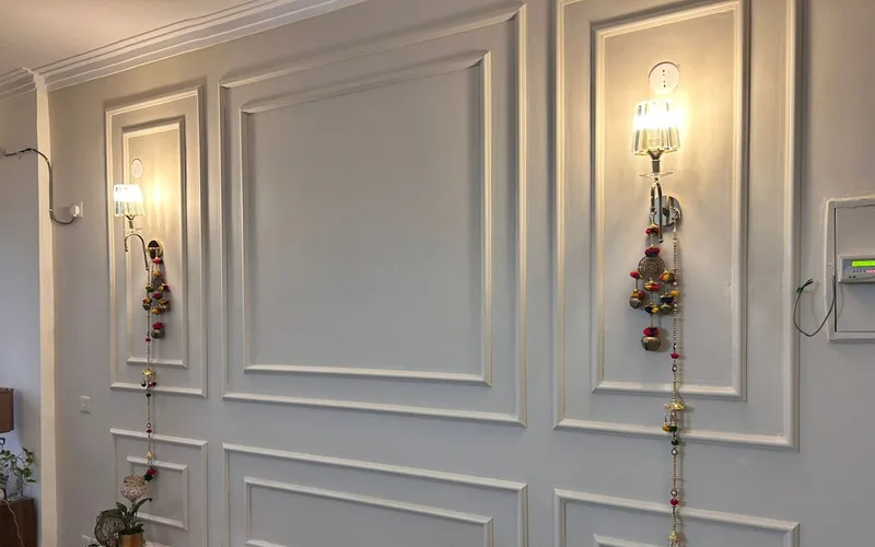 Living room wall in white moulded panelling with a decorative wall light