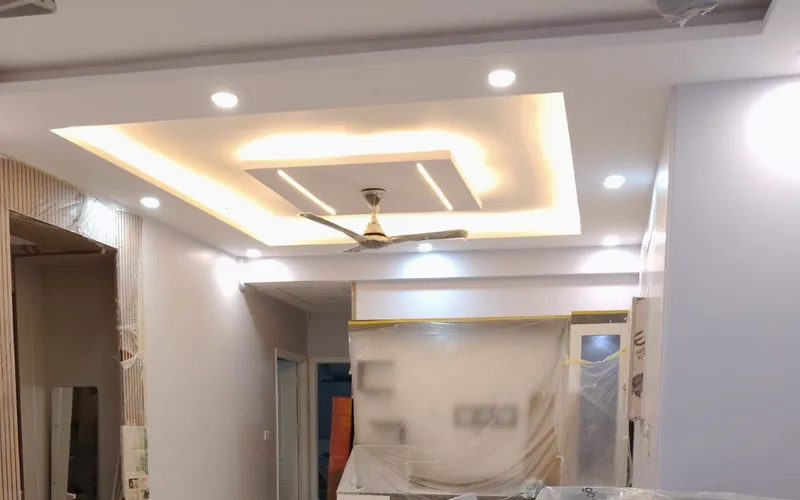 Apartment corridor mid-renovation with covered furniture and a finished cove ceiling