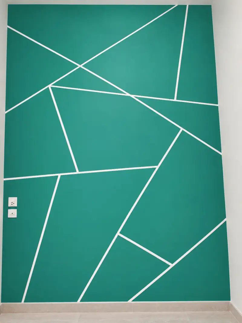 Deep teal feature wall divided into geometric facets by straight white lines
